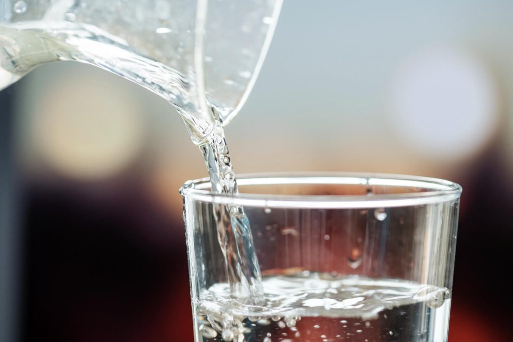 Filtered water is poured from a jug into a glass.